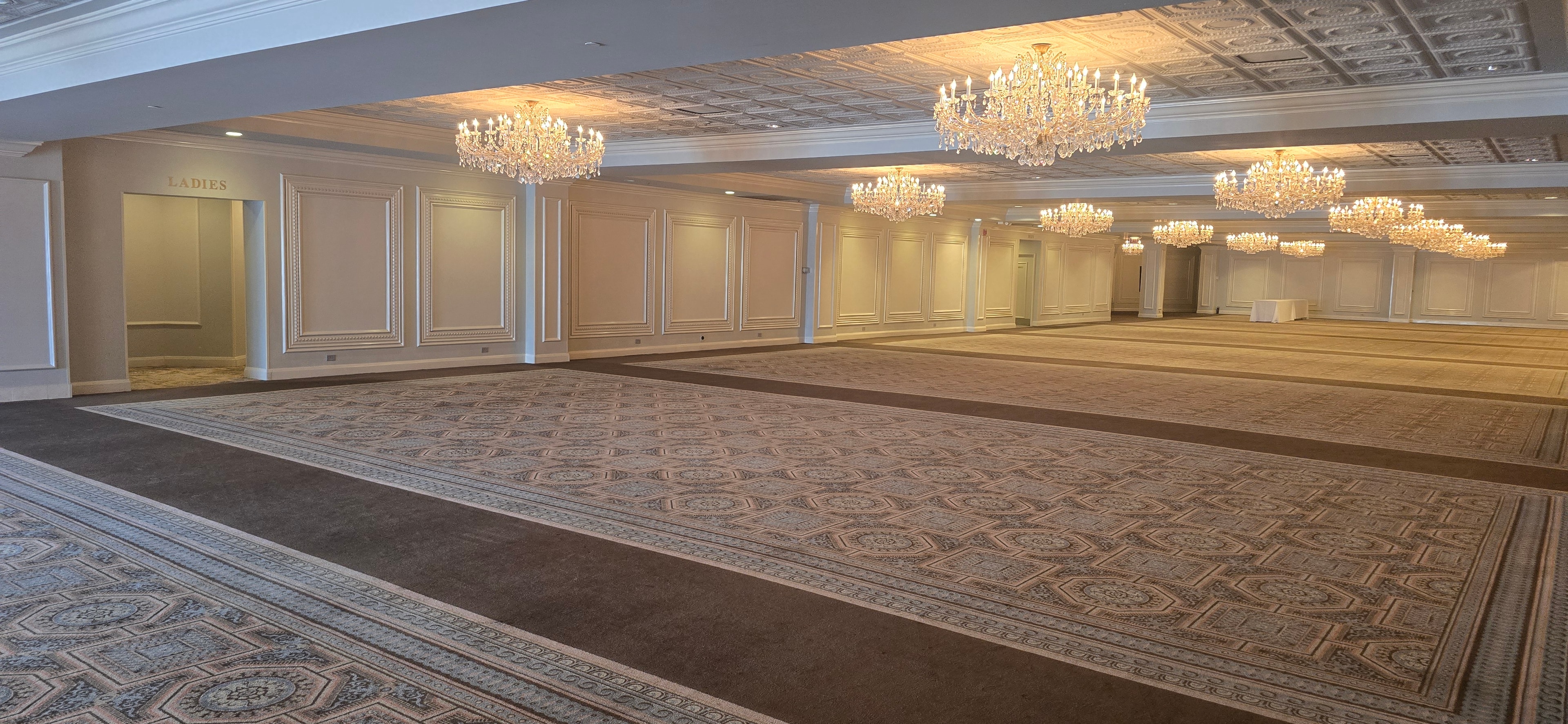 Drury Lane Grand Ballroom interior — crystal chandeliers, ornate carpeting, and panelled walls showing the full scale of the venue for the 2026 RUSH University Graduation